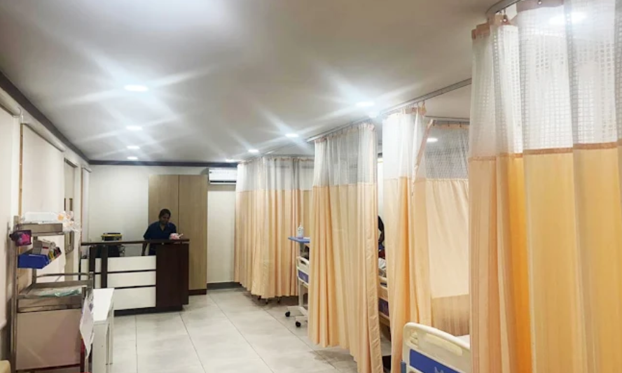 Inpatient recovery ward at HCAH SuVitas Rehabilitation Center featuring hospital beds separated by medical privacy curtains and a nursing desk in the background.